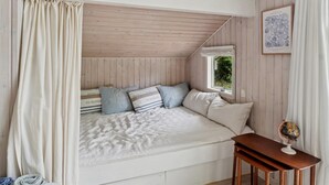 A cozy bedroom with a sloped ceiling, a bed with striped bedding, a small table with a globe, and a framed botanical illustration on the wall. - "Tekla" -  from the sea by Interhome (Rørvig)