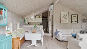 A spacious living area with a white sofa, a dining table with a white tablecloth, and a kitchen in the background. - "Tekla" -  from the sea by Interhome (Rørvig)