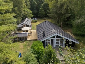 Une propriété résidentielle comprenant une maison principale et un garage séparé, le tout entouré d’une forêt dense.