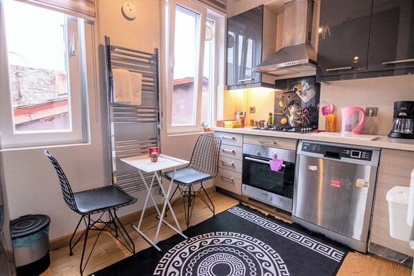 A compact kitchen with a dishwasher, oven, and a small dining area with a table and chairs.