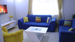 A living room with a blue sofa set, a white coffee table, and a yellow armchair.