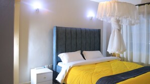 A bedroom with a bed, bedside table, and a hanging light fixture.