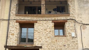 Un bâtiment en pierre de deux étages, doté d’une porte en bois, de deux fenêtres et d’un balcon avec des balustrades en métal.