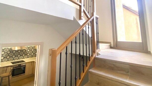 Un escalier avec des rampes en bois et des balustres noires menant à l’étage supérieur.