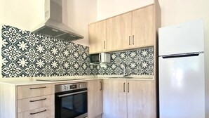 Une cuisine avec des meubles de rangement en bois, un four à micro-ondes, un four traditionnel et un réfrigérateur blanc.
