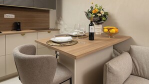 A modern kitchen with a wooden island, two grey chairs, a vase of flowers, and a bottle of wine. - Villa Maja Aurelia in the Centre- Romantic Studio Apartment (Hvar)