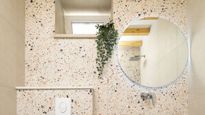 A compact bathroom with a white toilet, a small sink with a mirror, and a shelf with rolled-up towels. - Villa Maja Aurelia in the Centre- Romantic Studio Apartment (Hvar)