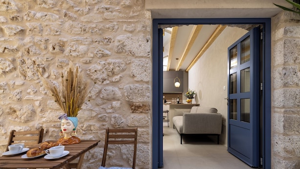 A rustic stone wall with a wooden table set for two, a chair, and a vase with dried plants. - Villa Maja Aurelia in the Centre- Romantic Studio Apartment (Hvar)