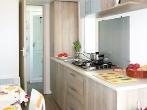 Cozinha compacta com fogão a gás, pia e armários de madeira.