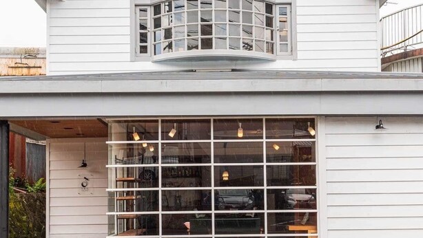 A modern building with a large glass facade, a curved window, and a visible interior with shelves and lighting fixtures. - Shimanto Hutte - Hostel (Shimanto)