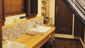 A modern bathroom with wooden cabinetry, a tiled backsplash, and a wooden vanity with two sinks. - Shimanto Hutte - Hostel (Shimanto)