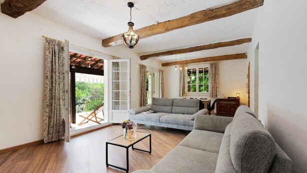 A spacious living room with a grey sofa, a wooden coffee table, and a hanging light fixture.