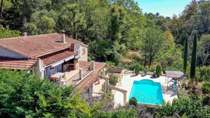 A villa with a swimming pool, outdoor seating, and a lush garden.