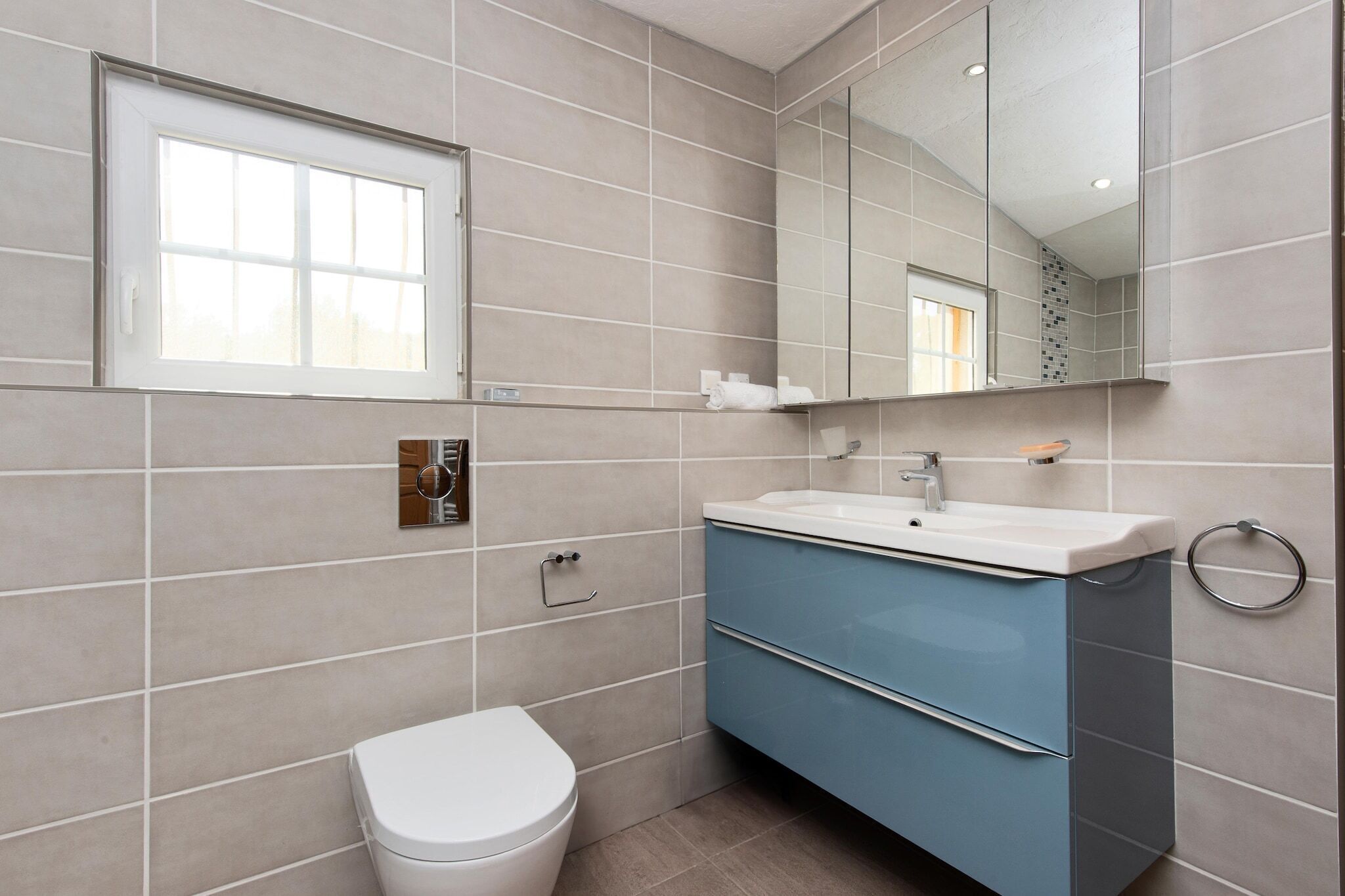 Een moderne badkamer met toilet, wastafel en spiegel.