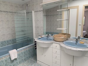 Ein Badezimmer mit zwei Waschbecken, einer Duschkabine aus Glas und einem Spiegel.