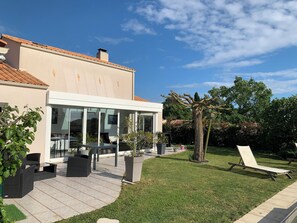 Ein modernes Haus mit Terrasse, Gartenmöbeln und Rasenfläche.