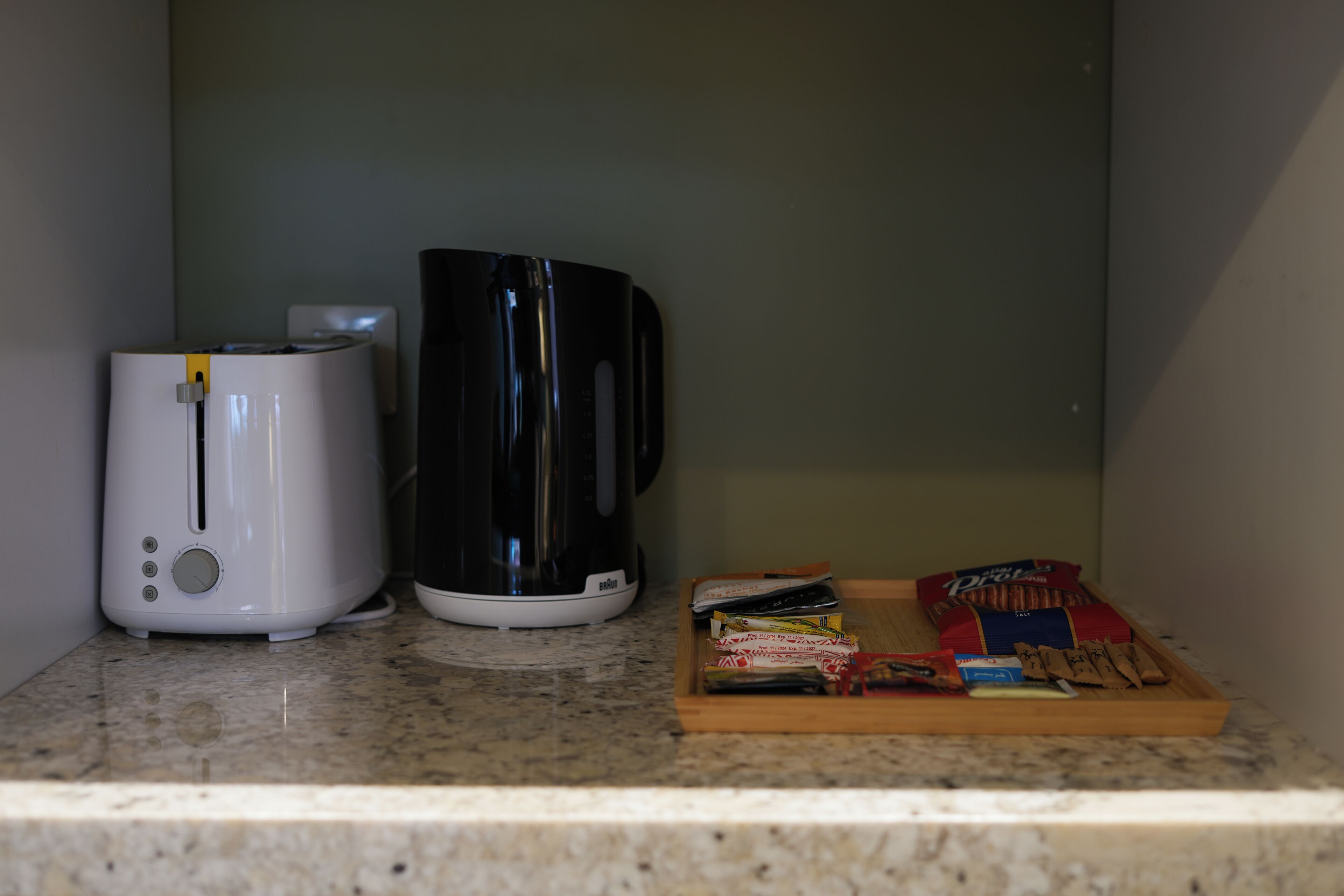 A kitchen counter with a toaster, a coffee maker, and a tray with snacks.