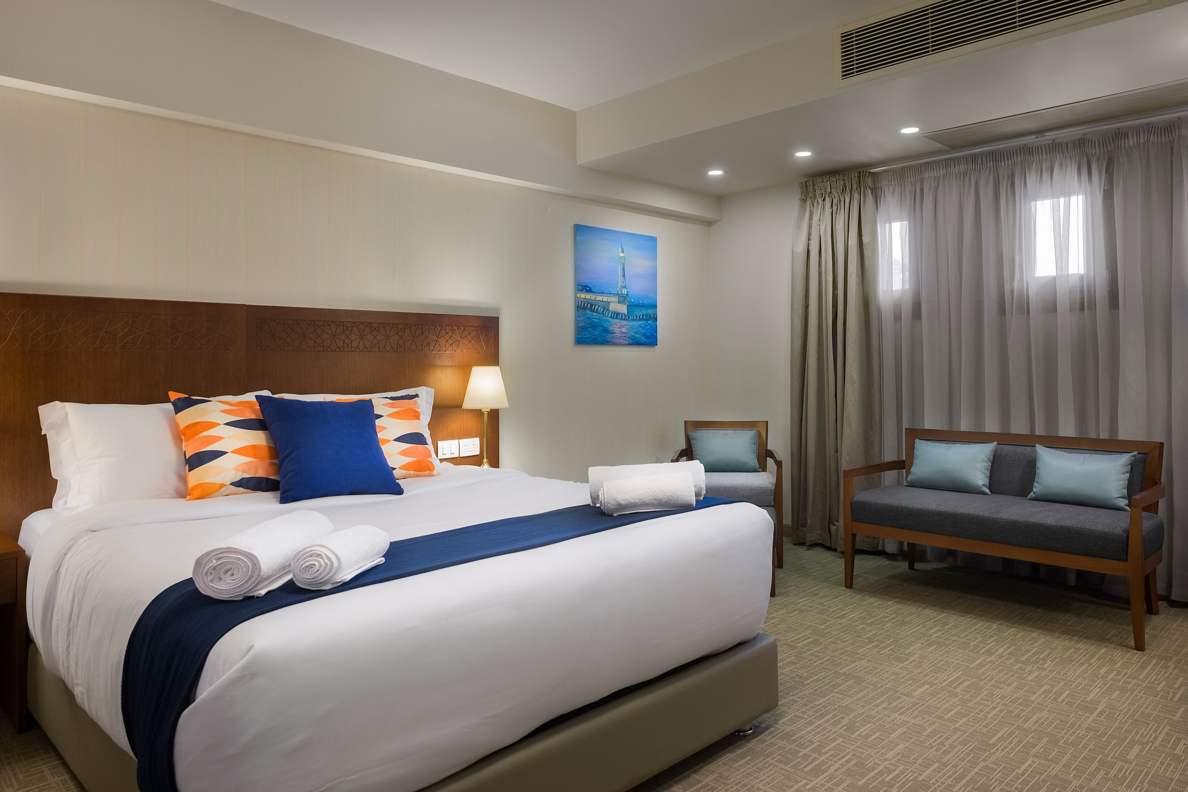 Une chambre d’hôtel avec un grand lit, un canapé, un fauteuil et un tableau au mur.