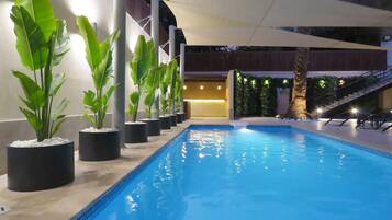 Una piscina al aire libre, sillones reclinables de piscina