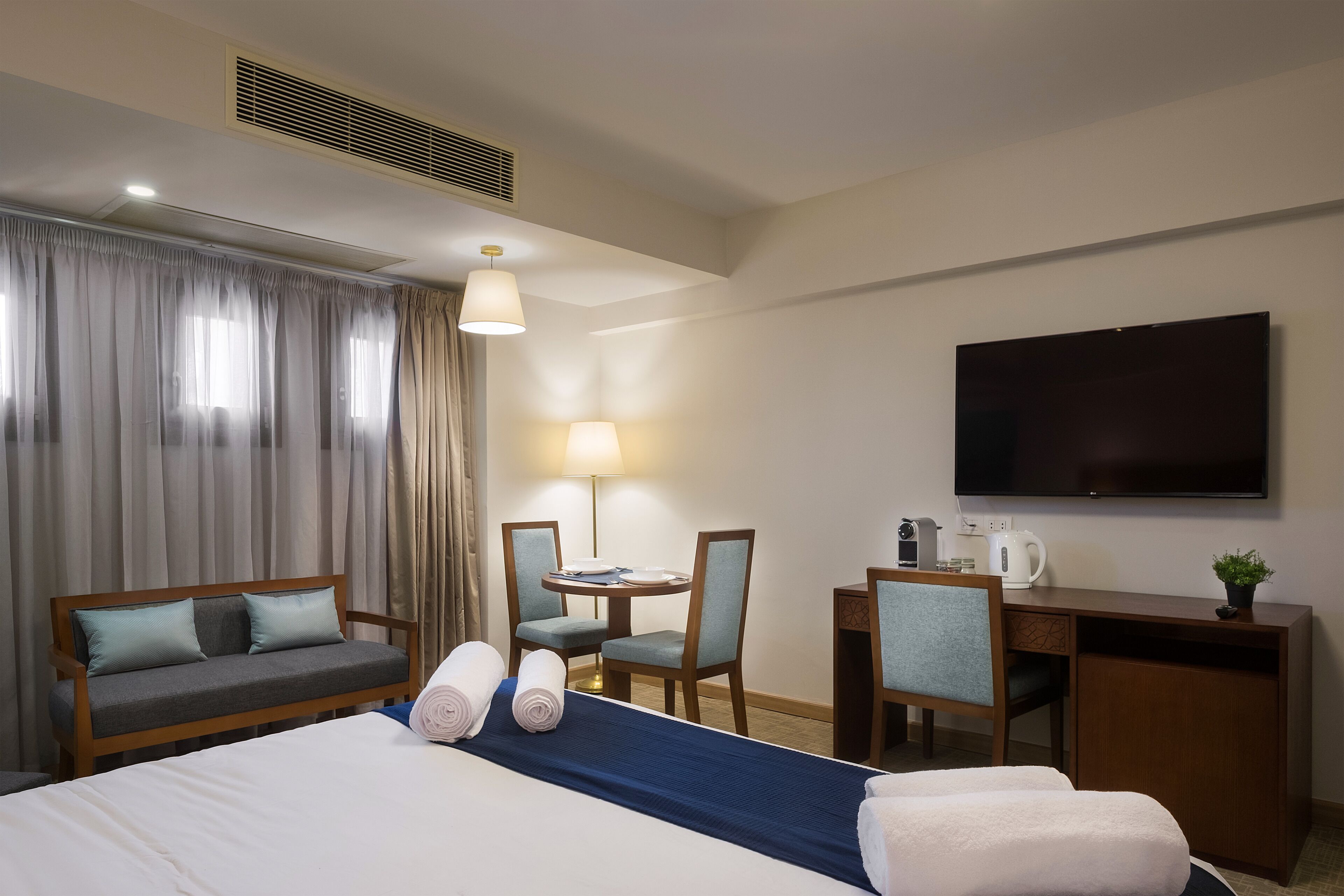 Une chambre d’hôtel équipée d’un lit, d’un bureau, d’une chaise, d’une télévision et d’une fenêtre avec des rideaux.