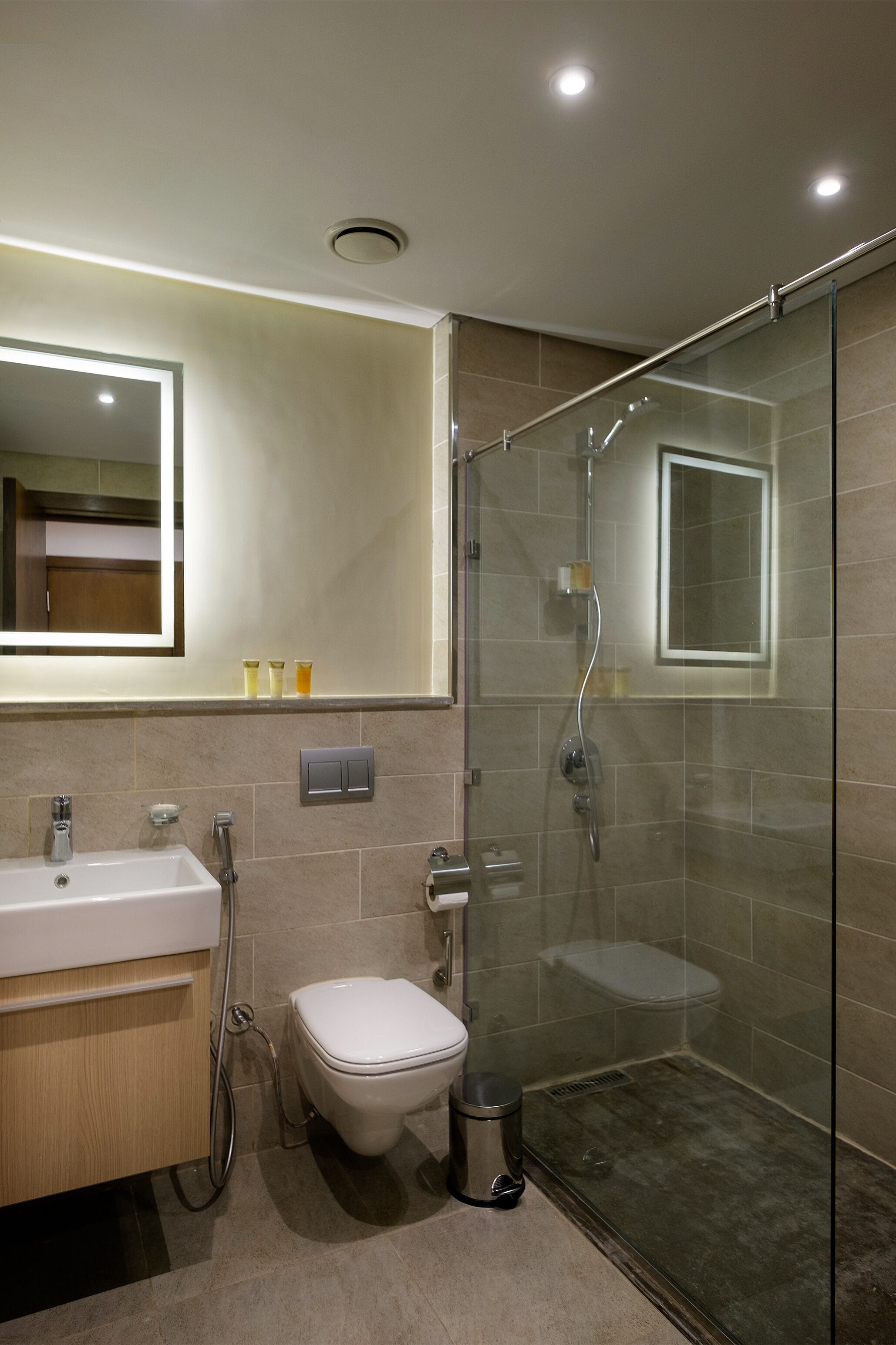 A modern bathroom with a glass-enclosed shower, a white sink, and a toilet.
