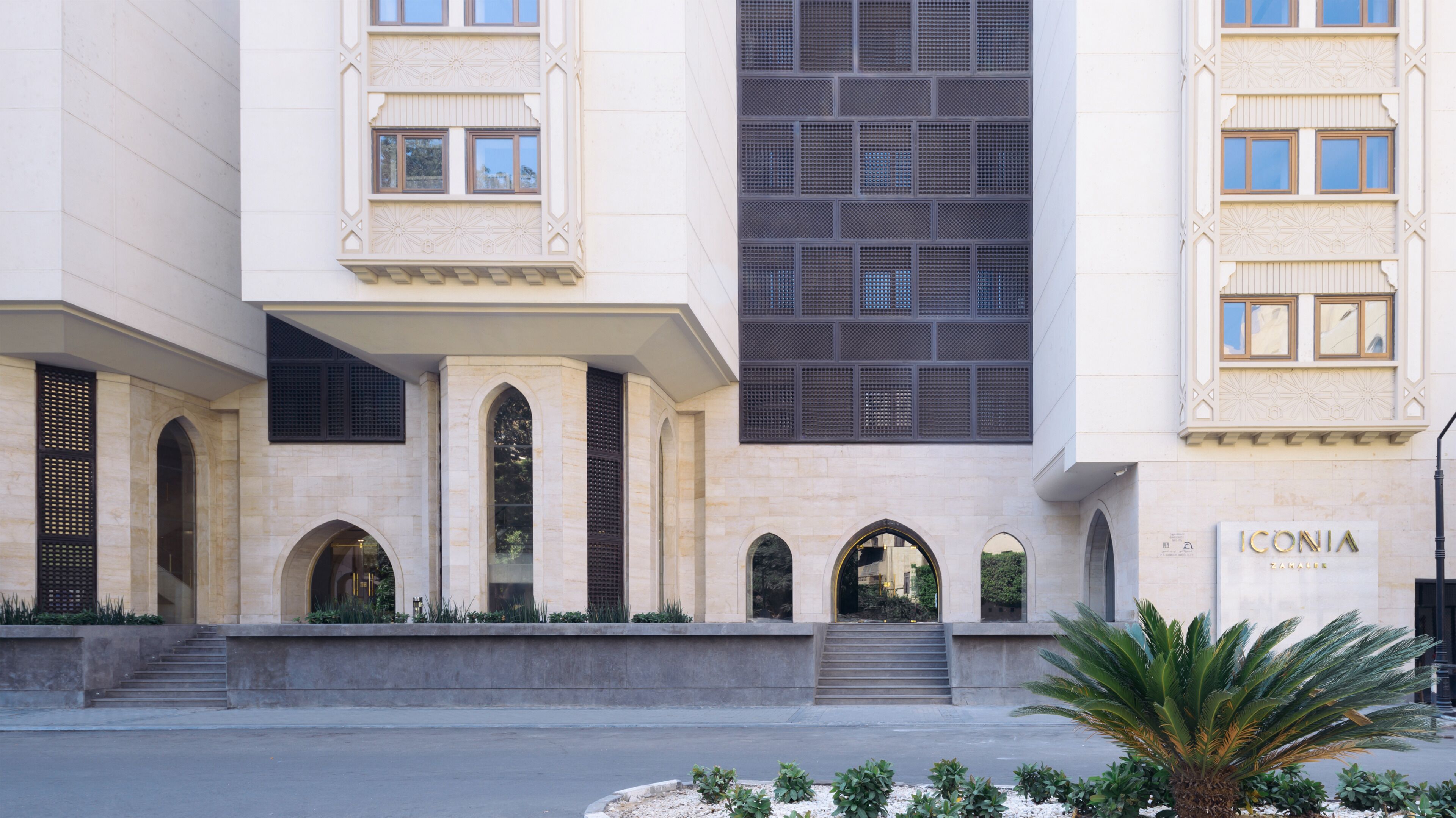 A building with arched doorways, a large window with a grid pattern, and a sign that reads "ICONIA ZANAKER".