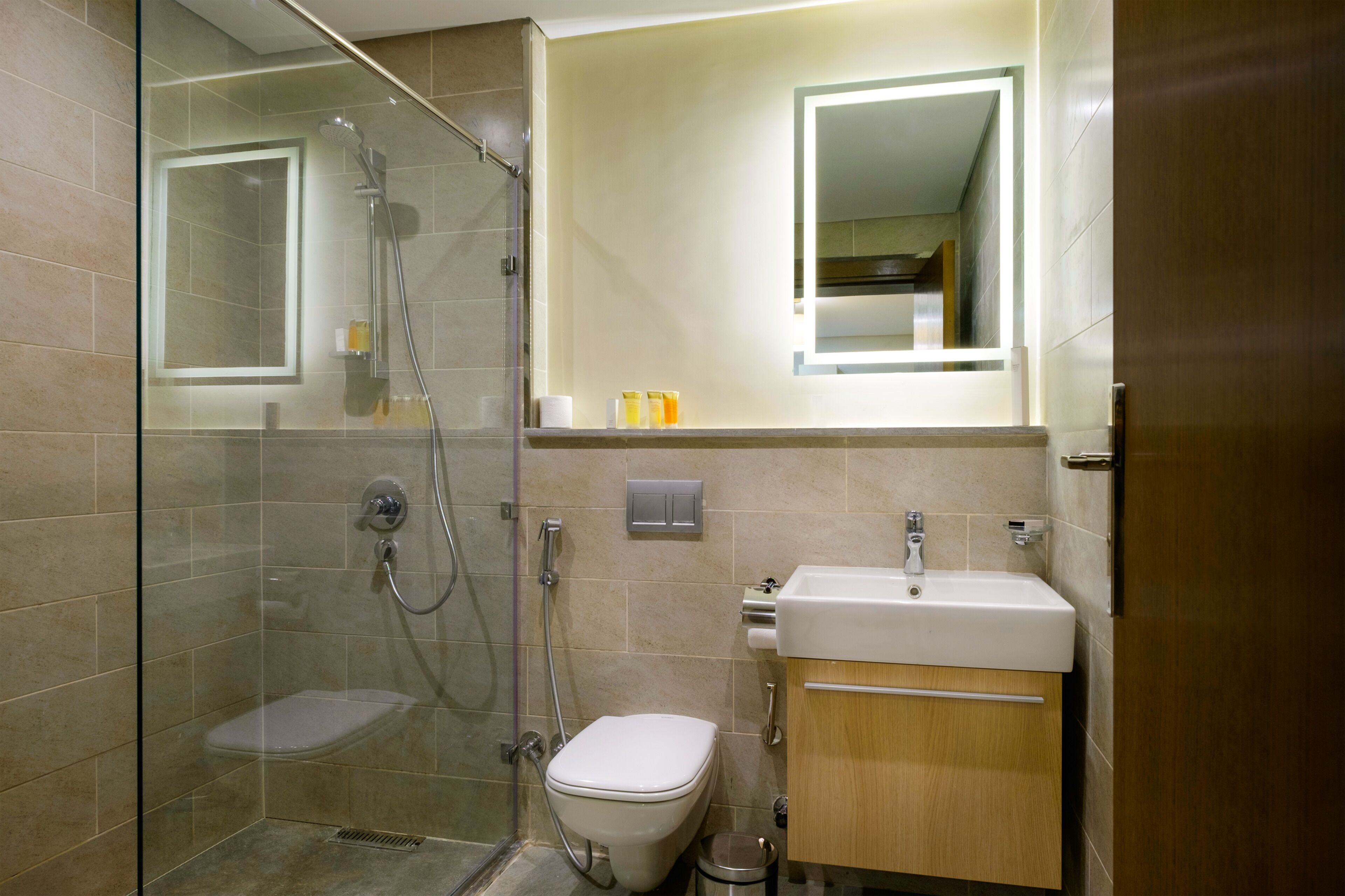 Un baño moderno con ducha de vidrio, inodoro y lavamanos con espejo.