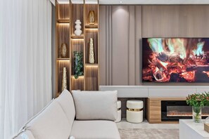 Una sala de estar moderna con un sofá, una chimenea, un televisor y estantes decorativos.