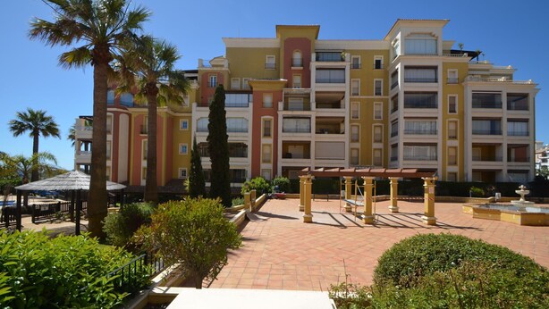 A multi-story hotel with balconies, a courtyard with palm trees, and a fountain. - Playa Grande 118 - Two Bedroom Apartment, Sleeps 5 (Punta del moral)