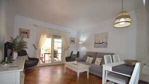 A living room with a sofa, chairs, a coffee table, and a dining table. There is a sliding glass door leading to an outdoor area. - Playa Grande 118 - Two Bedroom Apartment, Sleeps 5 (Punta del moral)