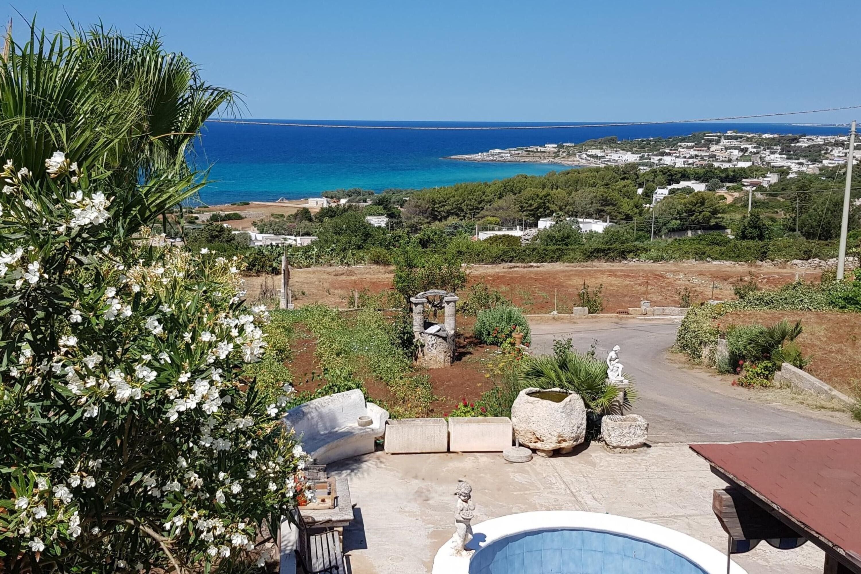 A pool area with a view of the sea and a town in the background.