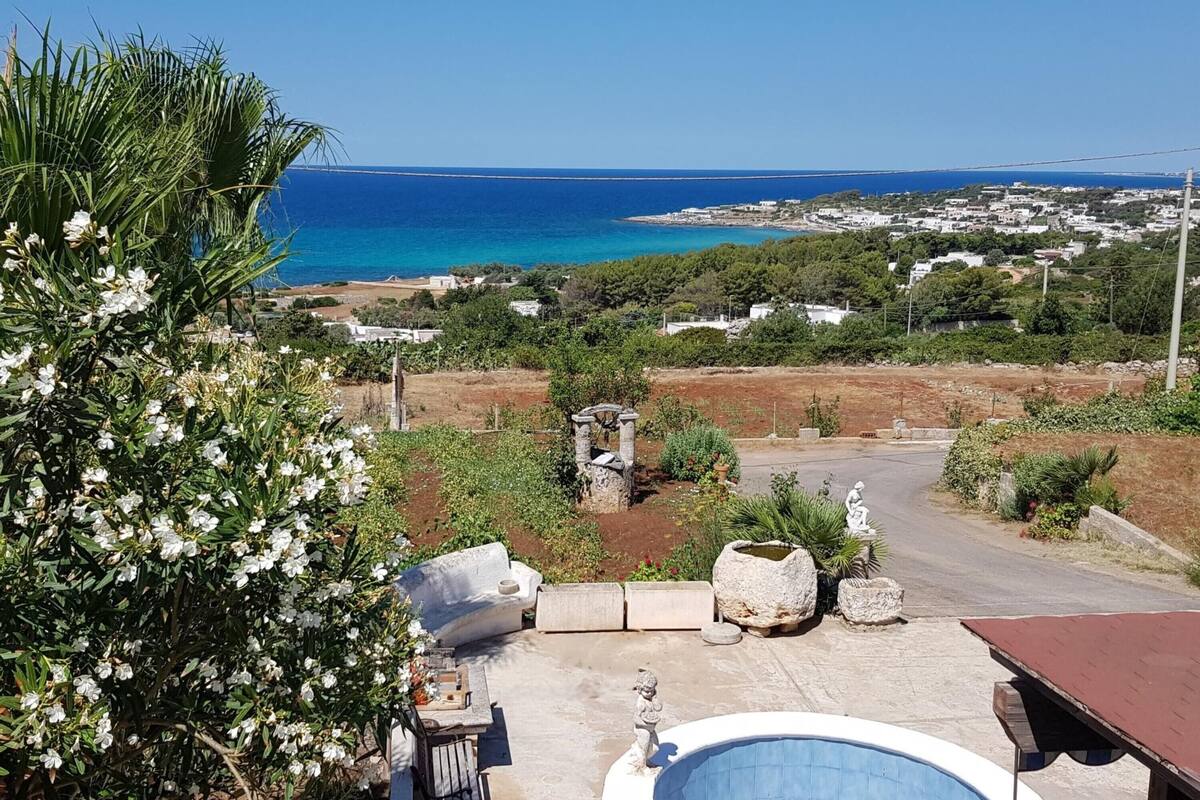A pool area with a view of the sea and a town in the background.