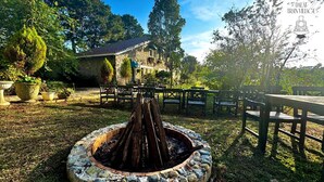 A stone building with a tiled roof, surrounded by a garden with benches and a fire pit. - Dalat Train Village (Lam Vien - Da Lat)