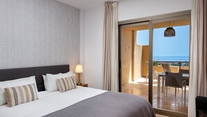 Une chambre d’hôtel avec un lit, une table de chevet, une lampe et une vue sur le balcon, qui est équipé de chaises et d’une table.