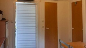 Een kamer met een houten plafond, een airconditioner, een schuifdeur en een tafel met stoelen.