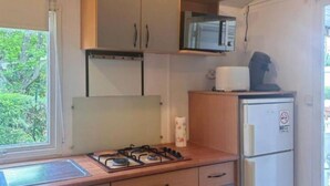 Een kleine keuken met een gasfornuis, magnetron en koelkast.
