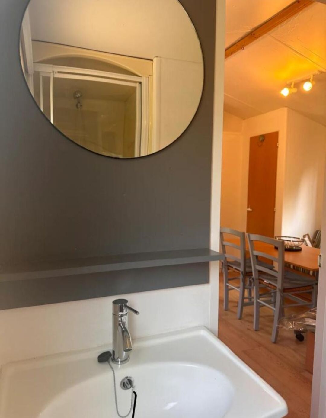 Een badkamer met een witte wastafel, een spiegel en een houten plafond.