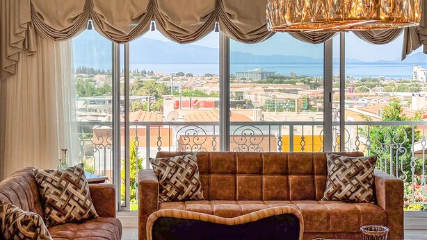 A living room with a sofa and armchairs, large windows with curtains, and a chandelier. - Villa Limon (Kusadasi)