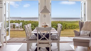 Un coin repas avec une table et des chaises, une horloge et une vue sur la mer.