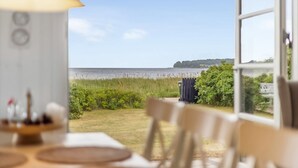 Une pièce avec vue sur un lac, une table à manger avec des assiettes et une lampe.
