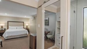Habitación de hotel con cama, mesita de noche, lámpara y vistas a un baño con ducha e inodoro.