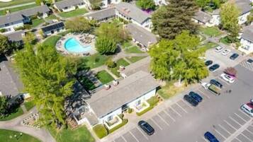 An aerial view of a residential area with houses, a swimming pool, and a parking lot.