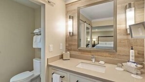 Un baño moderno con inodoro, lavamanos y espejo.