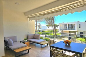 Relax on the balcony with a sofa, dining table, and chairs, offering a view of the surrounding buildings and greenery.