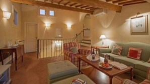 A cozy living room with a staircase, wooden beams, and a green sofa. - Duomo View Terrace By Belcanto Villas (Florence)