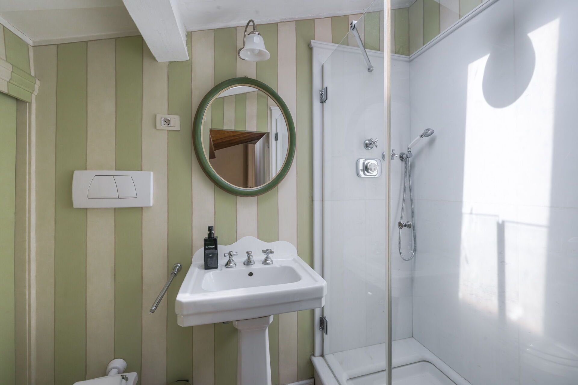 A bathroom with a white sink, a mirror, and a shower.