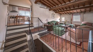 A spacious living area with a staircase, a green sofa, striped armchairs, and a dining area with a wooden table and chairs. - Duomo View Terrace By Belcanto Villas (Florence)