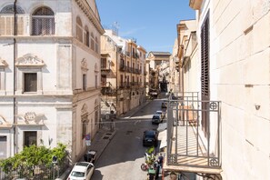 Una calle estrecha con edificios históricos, coches aparcados y cielo despejado.