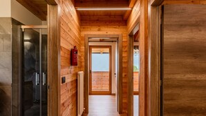A wooden hallway with a glass door on the left, a radiator on the right, and a fire extinguisher on the wall.