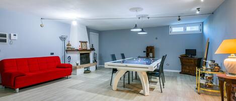 Un salón amplio con un sofá rojo, una mesa de futbolín y una chimenea.